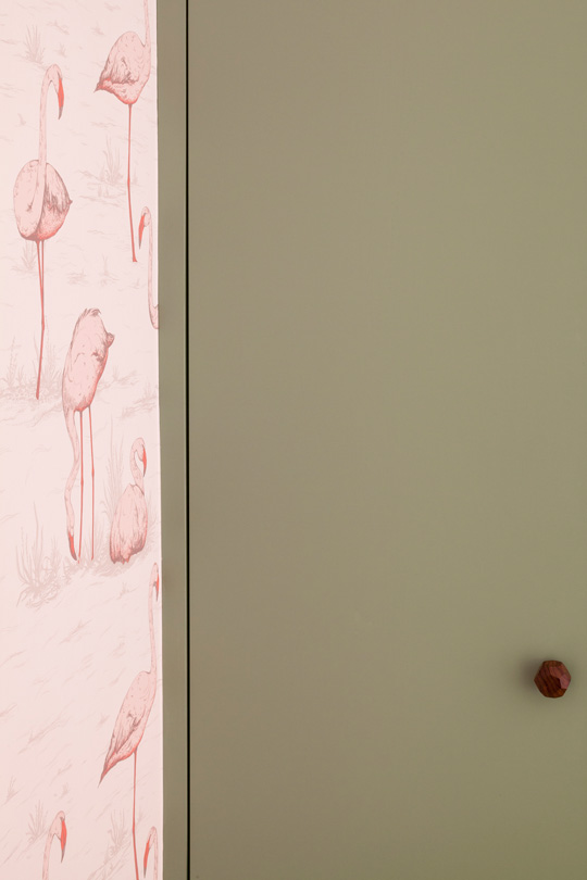 Pink cole and sons flamingo wallpaper beside a light green wardrobe